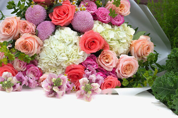 wedding bouquet or flower arrangement of pink and white roses, chrysanthemums, hydrangea lying on a table in a summer garden