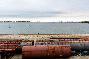 Large steel ducts and pipes rusty and abandoned in the dock of a harbour