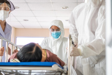 Front view of doctor and medical staff wearing protective face mask in a hurry taking patient on bed to operation room in hospital hallway. emergency theatre service and support during Covid19
