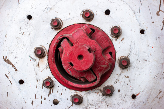 Vintage tractor large white steel wheel central hub and red bolts frontal view close up shot