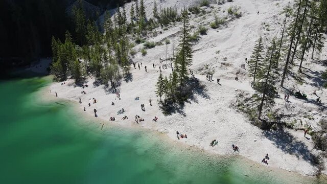 4k video of lake Braies in the dolomites, italian alps, with very high mountains around. high resolution, beautiful colors of nature, blue and green lake. small rowing boats with people.