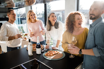 Happy five friends holding glasses with wine at home