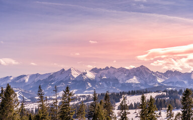 Fototapeta na wymiar Sunset with dramatic sky and panoramic view on forest and snowy Tatra Mountains in winter time. Ski slopes and ski lifts in Bialka Tatrzanska, Poland