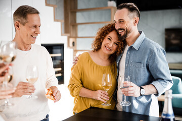 Smiling couple is posing at camera and holding wine