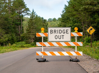 Orange and white striped road sign that reads "Bridge Out"