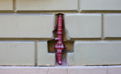 Red fire hydrant in the wall of the house