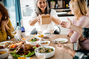 Smiling lady holding a gift at the festive table at home