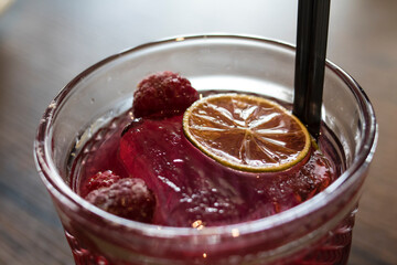 
Cocktail with raspberries and ice on a wooden table