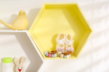 Hexagon shaped shelves with toys and child's accessories on white wall. Interior design