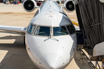 White airplane with jet bridge pulled up to it
