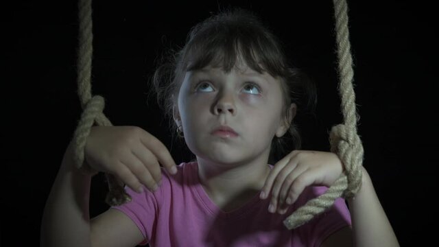 Get out from ropes. A little sad marionette unroped her hands and smile on the black background.