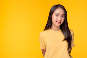 Portrait young asian woman, Beautiful girl wear yellow T shirt with yellow background, copy space at studio. Pretty asia female get confident. She has long hair
