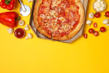 Tasty pizza and ingredients on yellow background