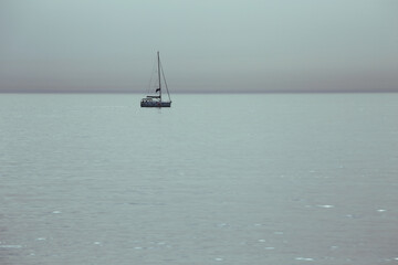 Little yacht on calm water of  the foggy sea
