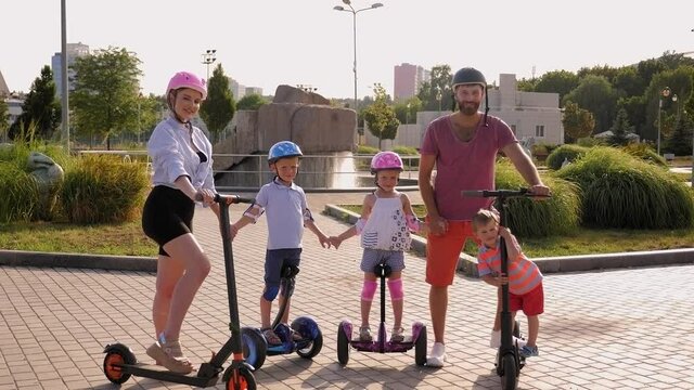 Portrait of family with kids on electric scooters and gyro scooter in the Park in the summer.