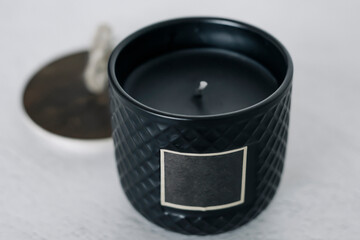 black candle on white table with wooden lid, place for text