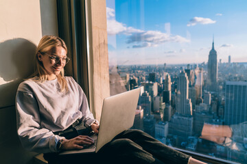 Millennial female freelancer reading web news during wireless browsing on digital laptop with 4g internet connection, youthful Caucasian blogger using netbook device for social communication