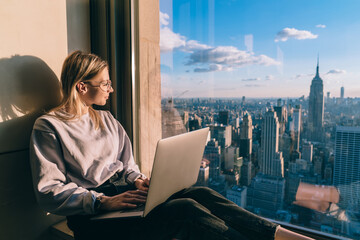 Caucasian woman in trendy clothing looking in window on metropolitan downtown admire beauty of...