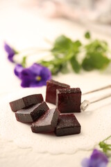 Handmade marmalade of dark color from grapes, on a white background.
