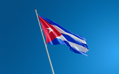 Isolated Cuba flag waving in the wind against blue sky background. Cuba national flag close up