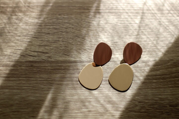 Pair of golden statement earrings, illuminated by sunlight. Selective focus.