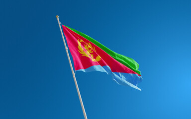Isolated Eritrea flag waving in the wind against blue sky background. Eritrea national flag close up