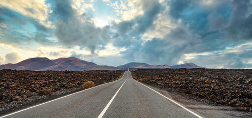 panoramic view of long straight empty road through volcanic landscape on Lanzarote, Canary Islands