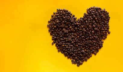 coffee seeds in shape of heart on yellow background