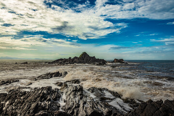 Fototapeta na wymiar rocky sea beach with crashing waves and amazing sky at morning from flat angle