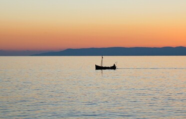 Fototapeta premium Fishing boat at sunset around the bay of Kardamyli village in Messiniaki Mani region of south Peloponnese in Greece.