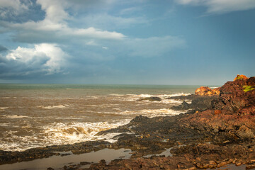rocky sea beach with crashing waves at morning from flat angle