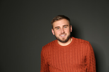 Fototapeta premium Handsome man wearing warm sweater on dark background