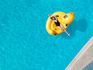 Top view aerial photo of a pretty model in black swimwear in pool.