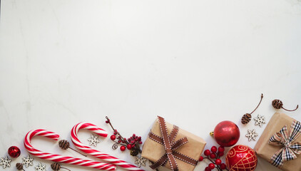 Gift boxes packed in brown paper and tied with ribbon, Christmas red toys and lollipops,pine cones and snowflakes, red berries on white background,top view,copy space.Christmas and New Year concept