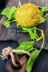 Small balls of Swiss hard cheese Belper Knolle, made from cow's milk. A round yellow fresh ball of cheese lies on a beautiful old wooden Board with lettuce leaves. Cheese is served with vegetables