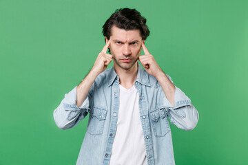 Displeased preoccupied young brunet man 20s wearing casual clothes white t-shirt denim shirt posing...