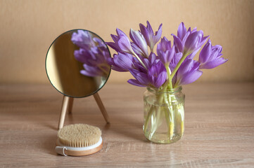 purple flowers mirror and massage brush on beige background