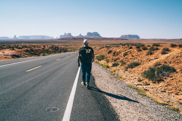 Man with backpack walking on route in desert