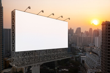 Blank white road billboard with Bangkok cityscape background at sunset. Street advertising poster, mock up, 3D rendering. Side view. The concept of marketing communication to promote or sell idea.