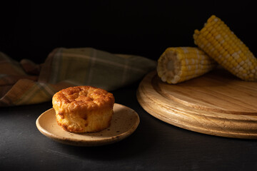 Golden Cornbread Muffin on rustic plate over dark background. Corn cobs. Dark rustic background. 