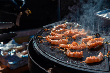 A professional cook prepares shrimps on the grill outdoor, food or catering concept