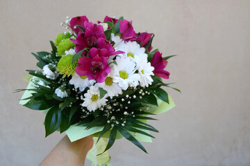 Unrecognizable person holding a bouquet with pink, white and green flowers. Selective focus.