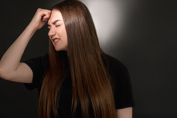 Hurt woman portrait. Domestic violence. Frustrated overweight lady in black t-shirt suffering from headache with closed eyes isolated on dark illuminated copy space background.