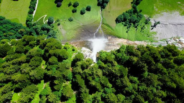 Aerial view over Staubbach Falls in Switzerland. A waterfall surrounded by the green forest of the Alps - 4K in drone view above the cliff