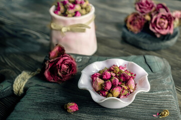 Flower tea rose buds in a white vase on an old wooden table. Close up