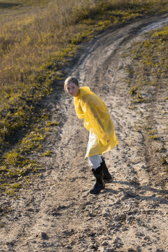 woman in yellow raincoat slipping on a muddy country road
