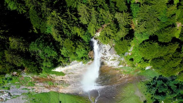 Aerial view over Staubbach Falls in Switzerland. A waterfall surrounded by the green forest of the Alps - 4K in drone view above the cliff