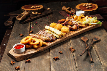 Fried beer snacks on the wooden board with sauces