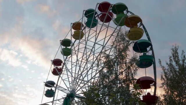 Ferris wheel attraction at sunset sky in the clouds