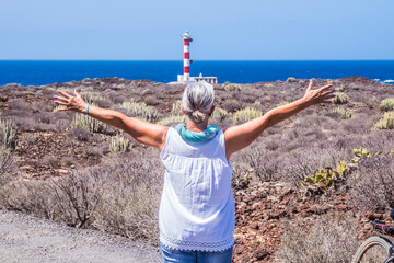 Rear view of a senior woman white haired and raised arms enjoying excursion and freedom with...